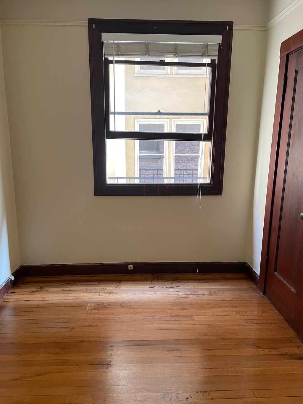 an empty room with a window and wooden floors